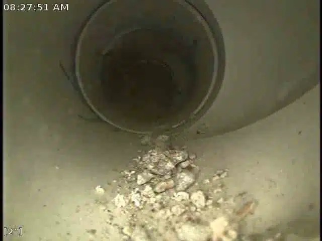 Screenshot of sewer inspection footage with debris in the bottom of a sewer pipe.