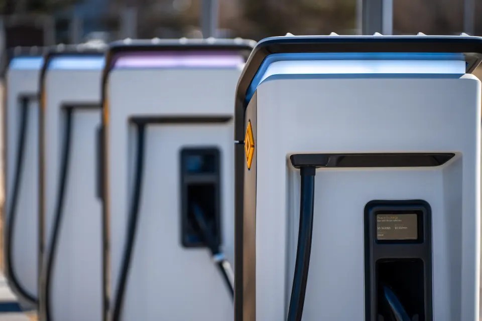 Row of EV charging stations with cables and plugs, ready for electric vehicle charging.