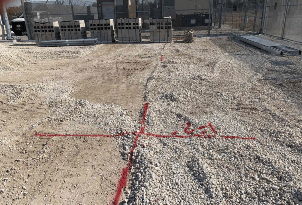Underground electrical utilities marked in red paint at an electrical substation, indicating verified utility locations prior to excavation.