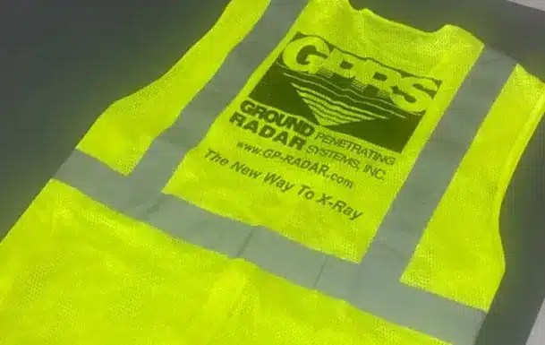 A bright yellow safety vest lying flat, featuring reflective gray stripes and the printed GPRS logo. Below the logo is the text “Ground Penetrating Radar Systems, Inc.” along with a website address and the tagline “The New Way To X Ray.