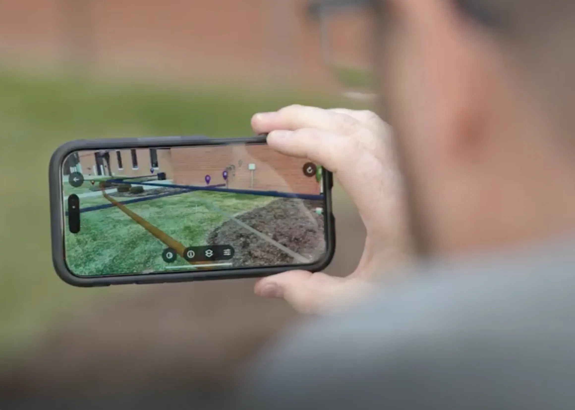 Person holding a smartphone displaying an augmented reality view of a building site
