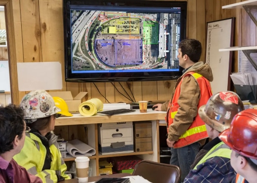 Construction team reviewing a site plan on a large monitor in a jobsite office