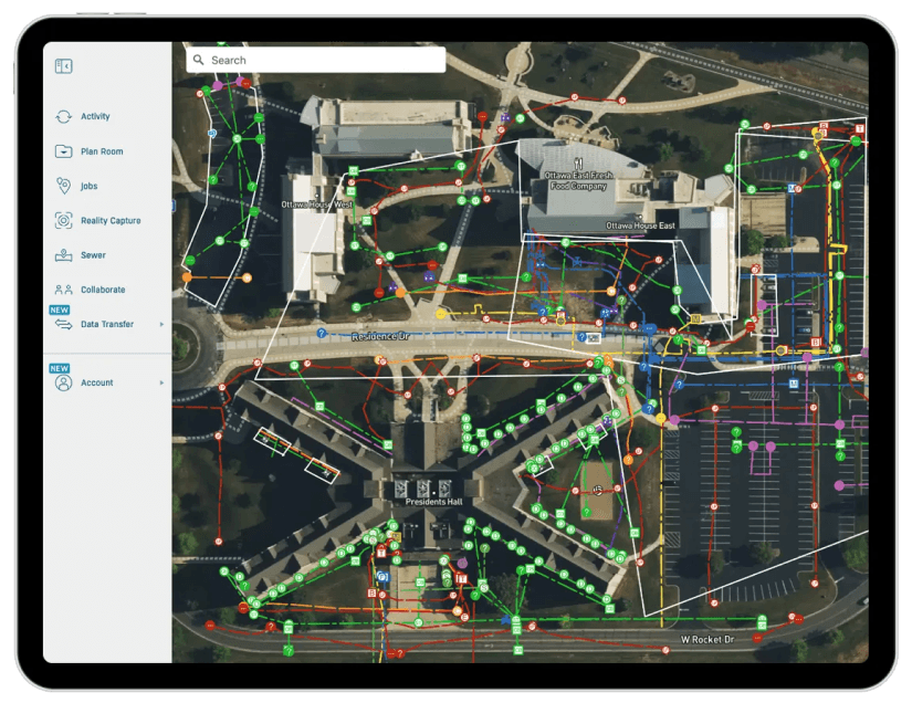 A tablet screen displaying a detailed aerial map of a campus‑style facility with multicolored utility lines, symbols, and pathways overlaid. A navigation sidebar on the left shows menu options such as Activity, Plan Room, Jobs, Reality Capture, and Data Transfer.